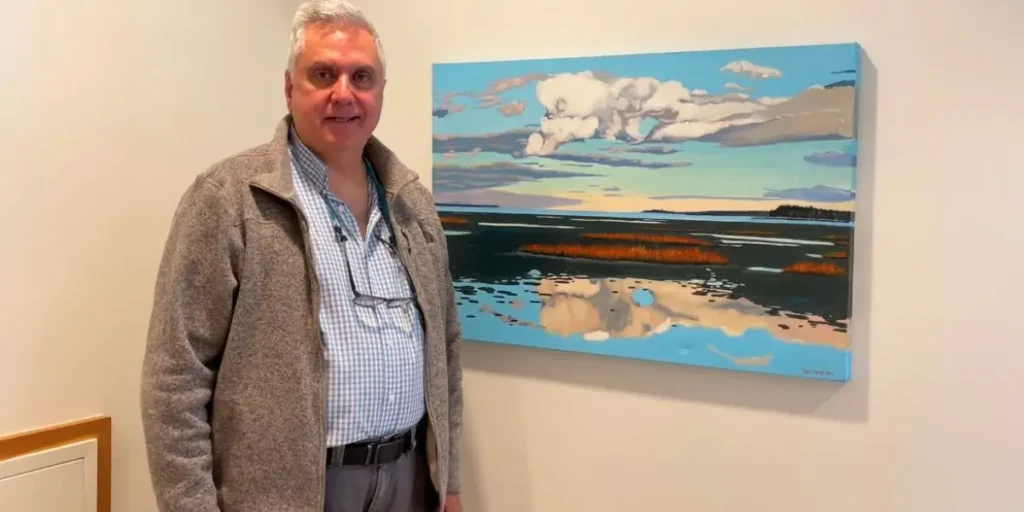 Dr. Louie Mavrogiannis standing next to a donated piece of art.