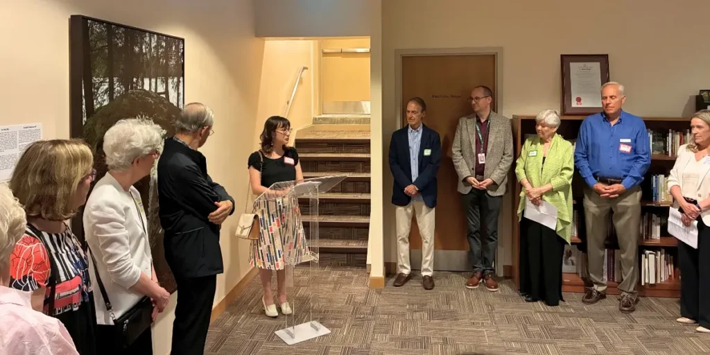 Guests listening to Sarina Isenberg of the Bruyère Health Research Institute make remarks at The Art of a Good Death exhibition launch at Dorothy Ley Hospice.
